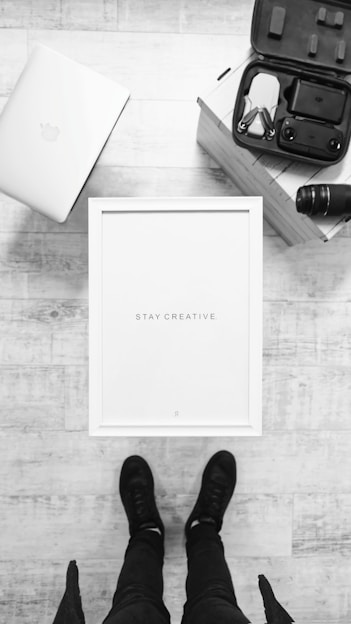A creative workspace with books, a laptop, and a DJI drone on a wooden table, bathed in soft natural light.