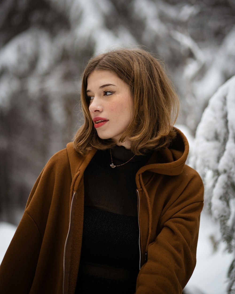 a woman in a brown jacket standing in the snow