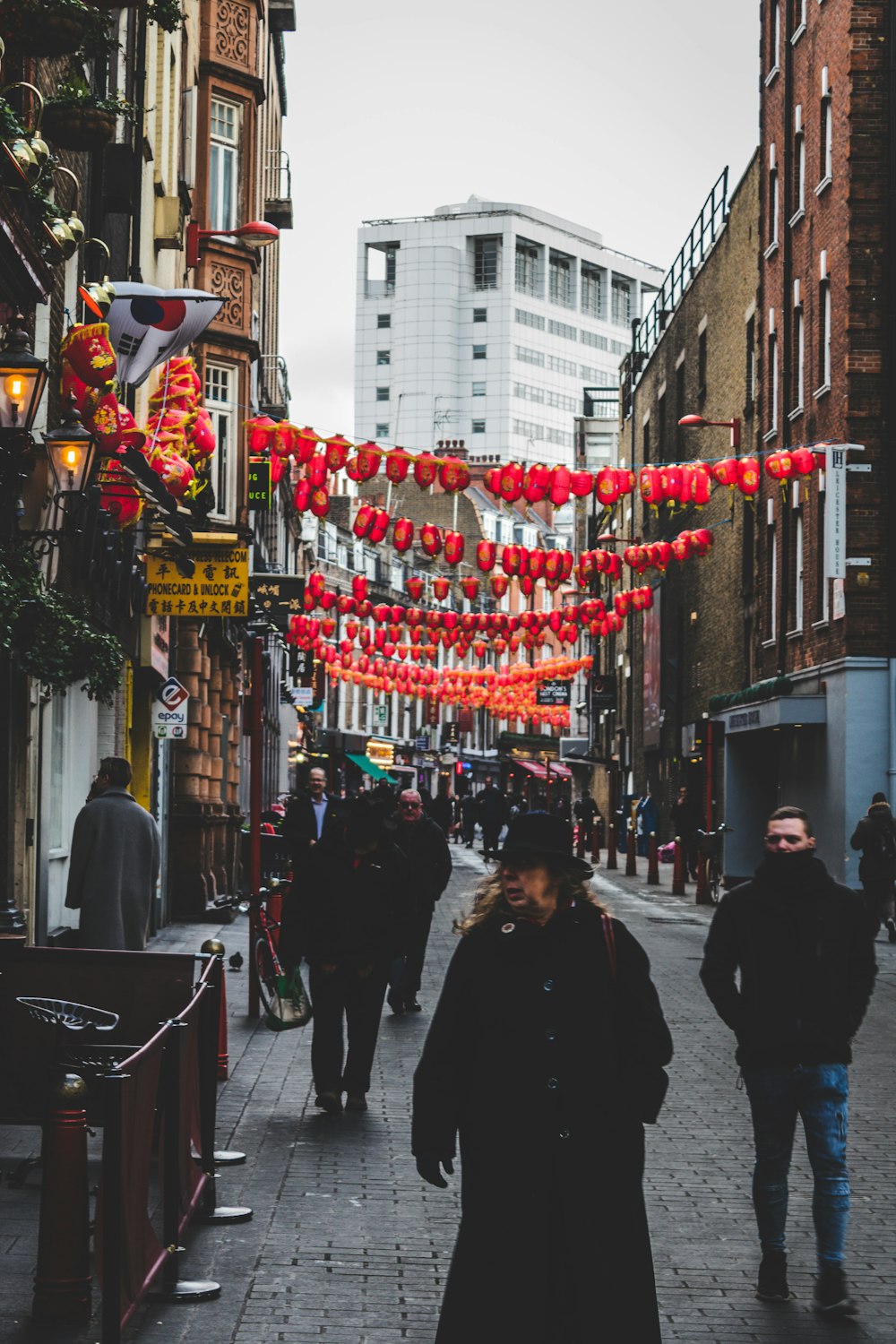 a group of people walking down a street next to tall buildings