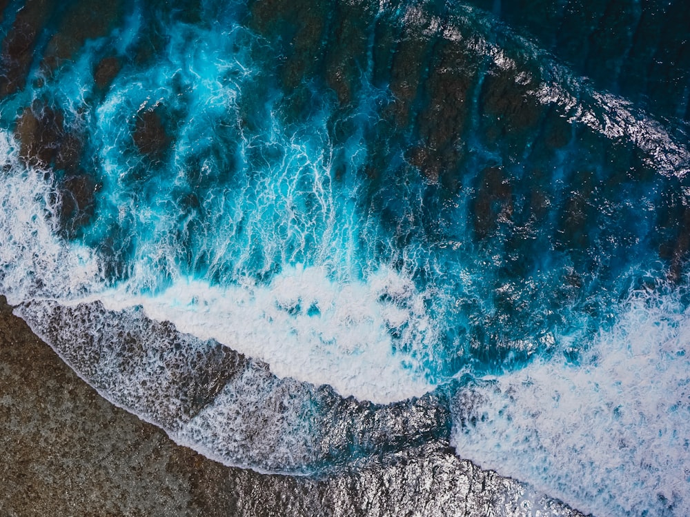 an aerial view of the ocean with waves crashing on the shore