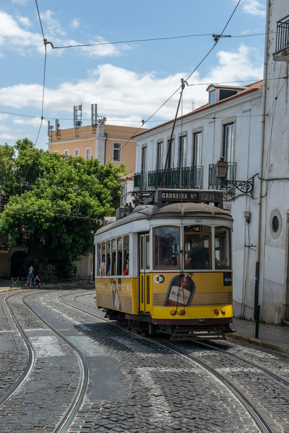 a yellow and white trolley car traveling down a cobblestone street