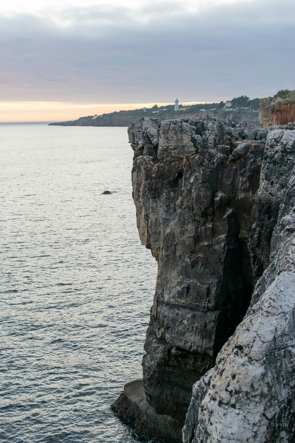 a person standing on the edge of a cliff near the ocean