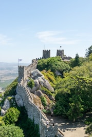 a very tall castle sitting on top of a lush green hillside