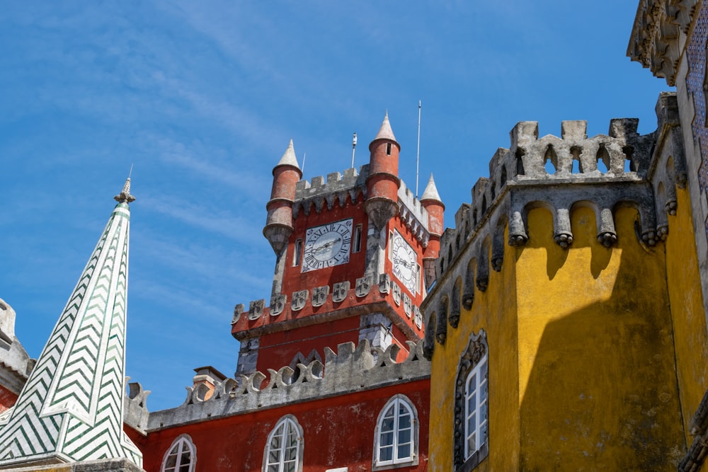 Una torre de reloj roja y blanca junto a un edificio amarillo
