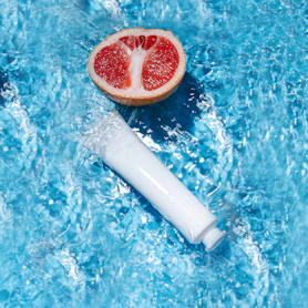 a grapefruit and a tube of water on a blue surface