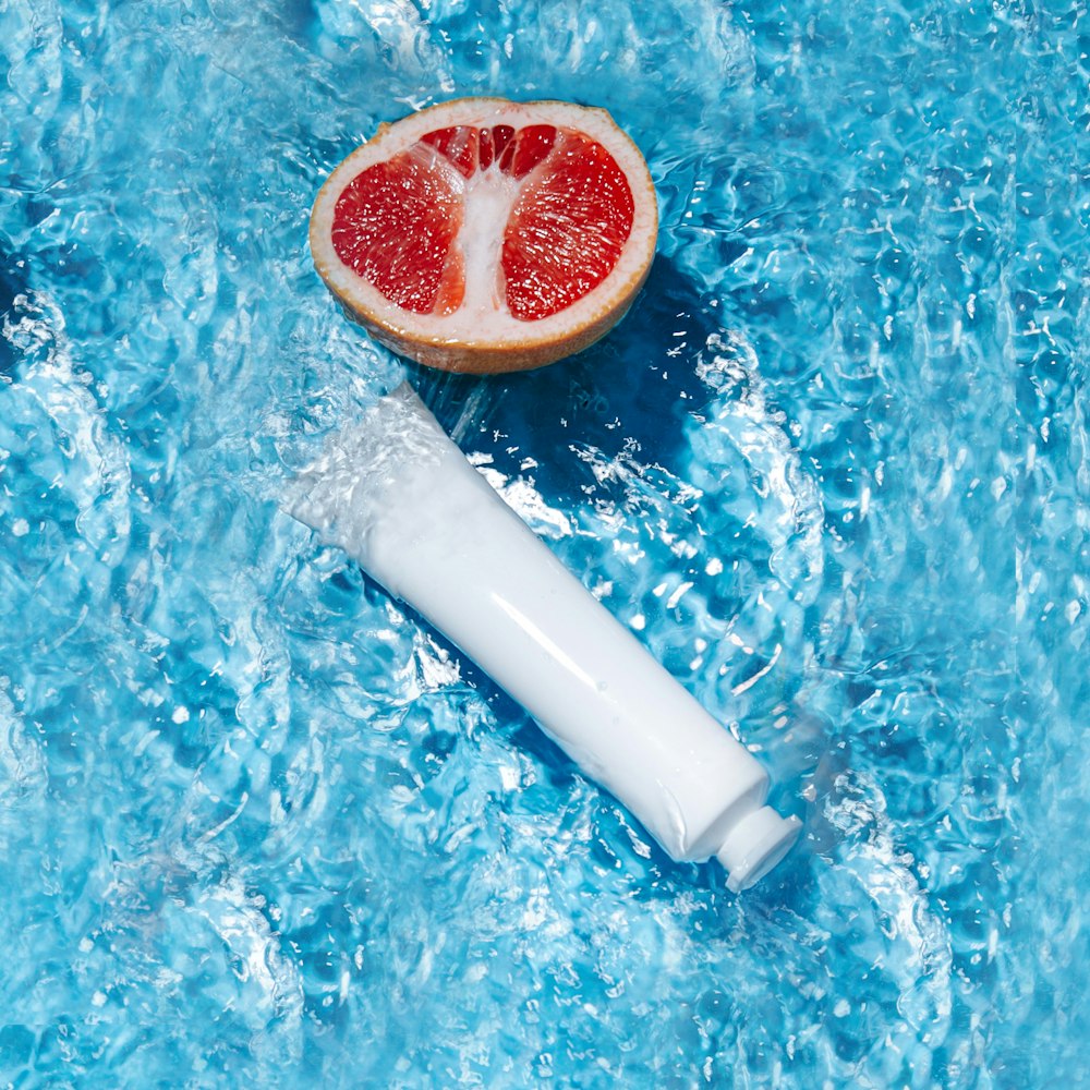 a grapefruit and a tube of water on a blue surface
