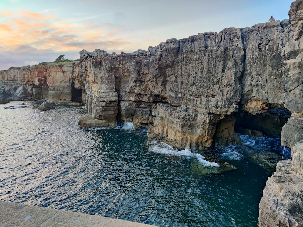 a large body of water next to a rocky cliff