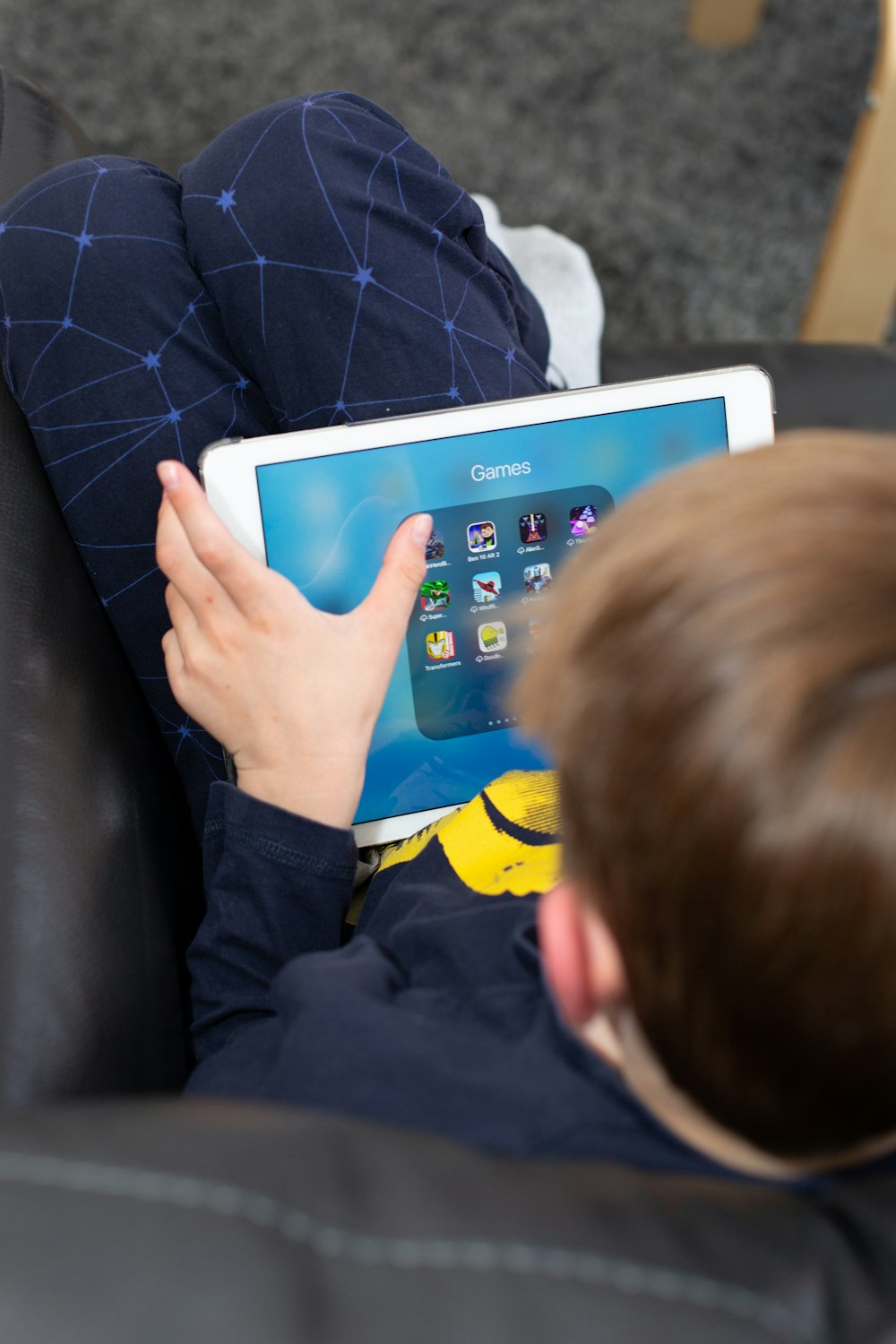 a young boy sitting on a couch holding a tablet