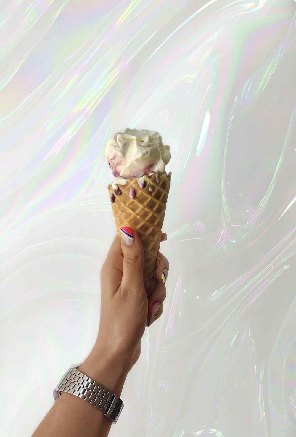 a hand holding an ice cream cone with white frosting