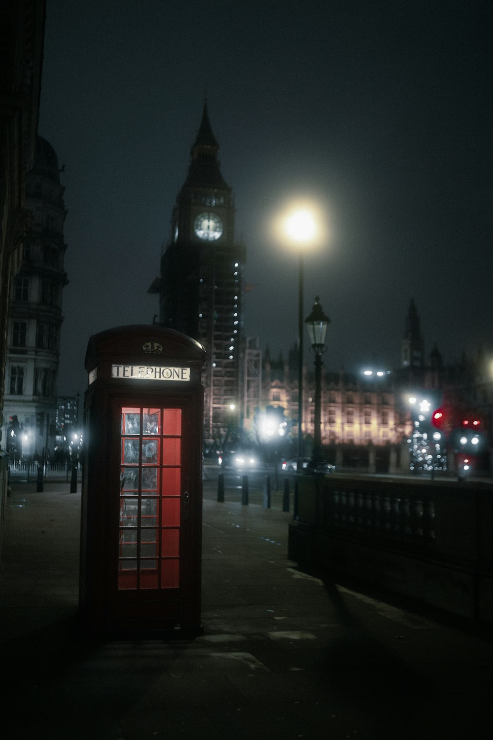 a red phone booth sitting on the side of a road