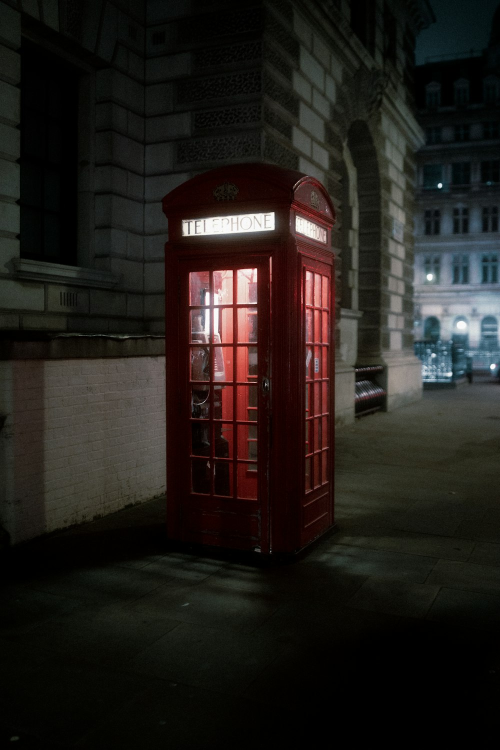 a red phone booth sitting in the middle of a street