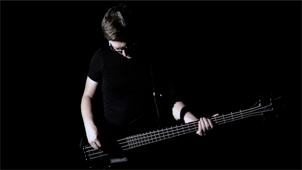 a man playing a bass guitar in the dark