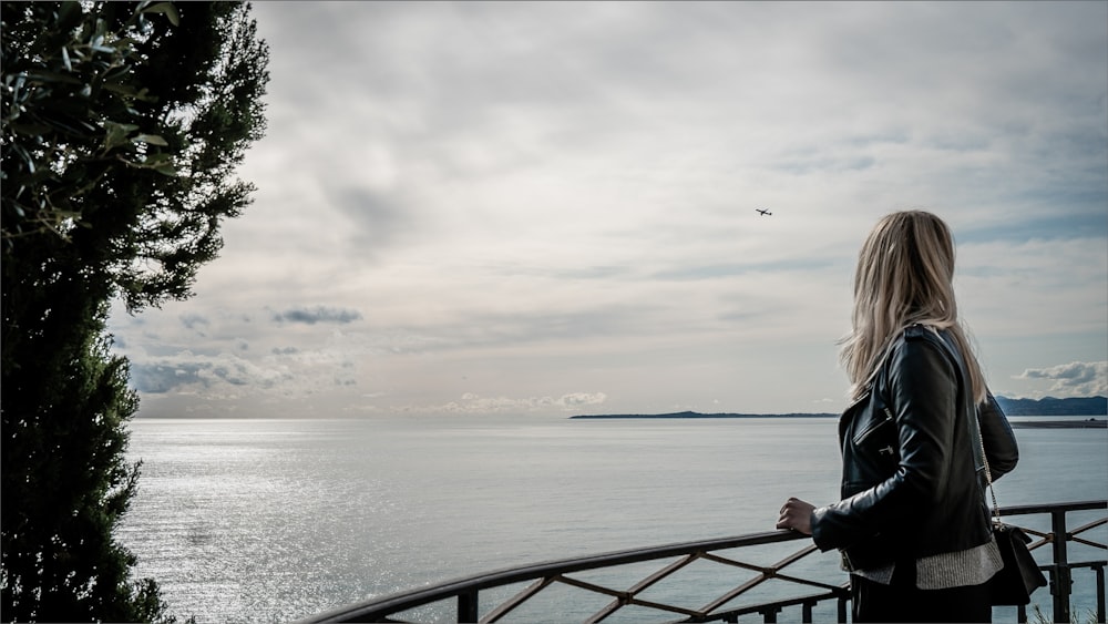 a woman standing on a balcony looking out at the water