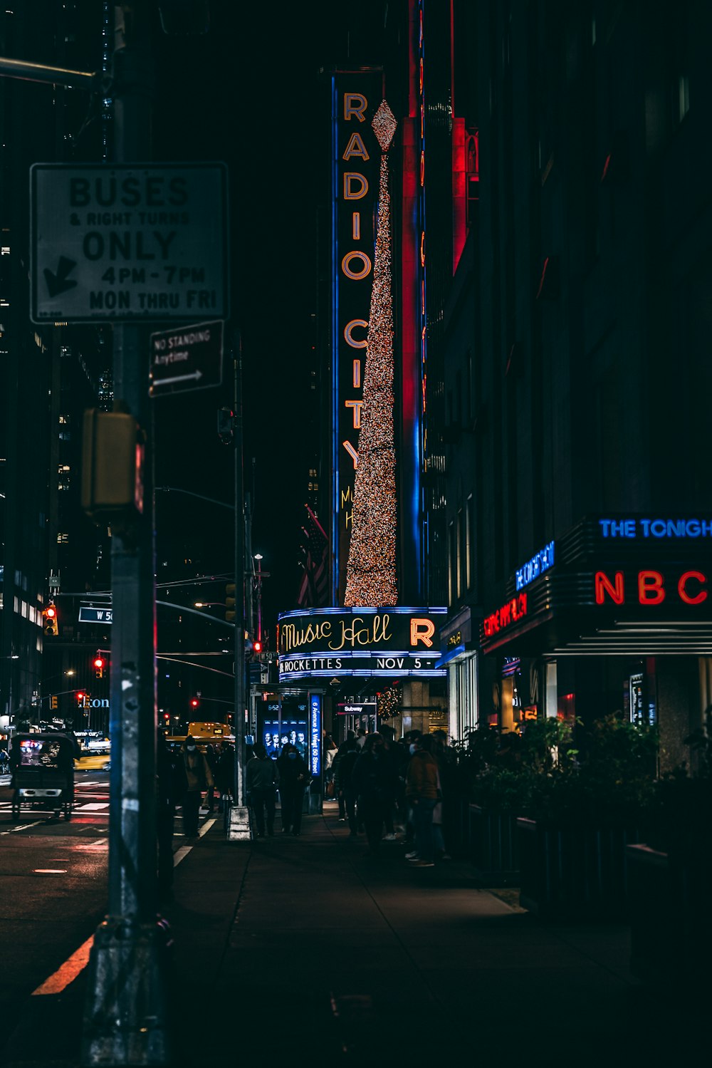 Una calle de la ciudad por la noche con un letrero de radio de la ciudad