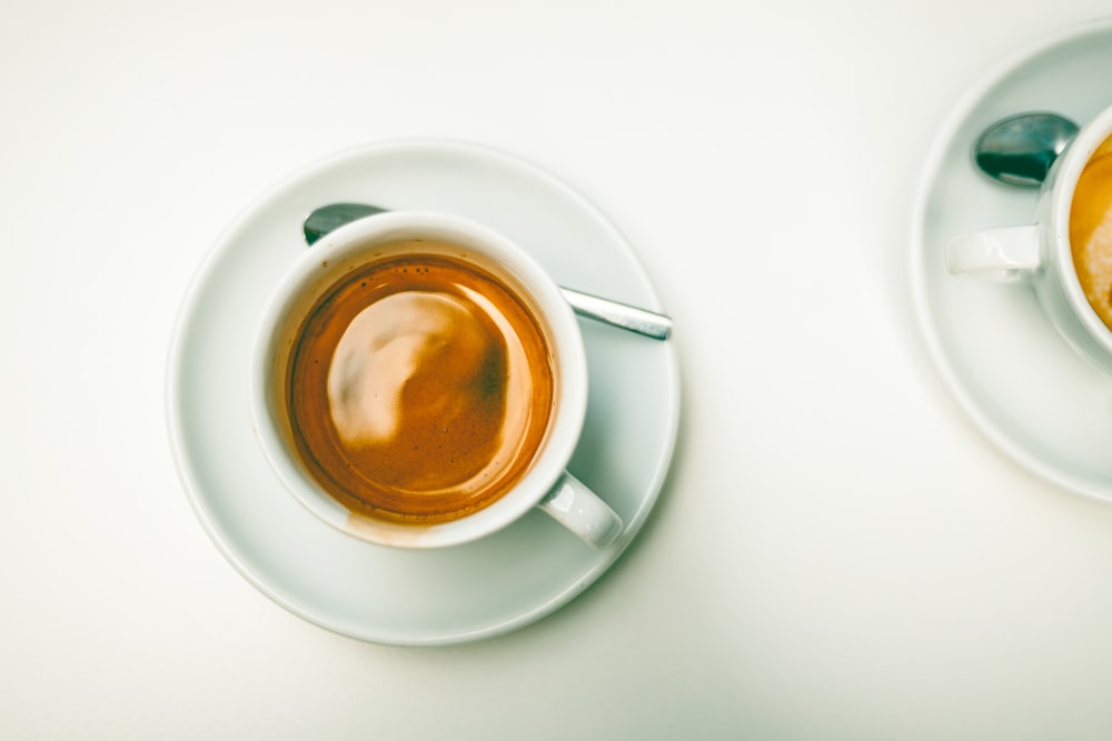 a cup of coffee on a saucer next to a spoon