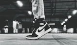 Street scene featuring a figure in monochrome streetwear with clean lines and polished sneakers, framed by soft natural light.