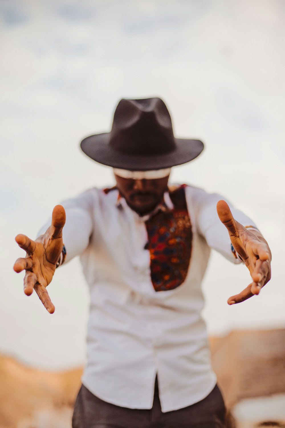 a man wearing a hat and a tie with his hands in the air