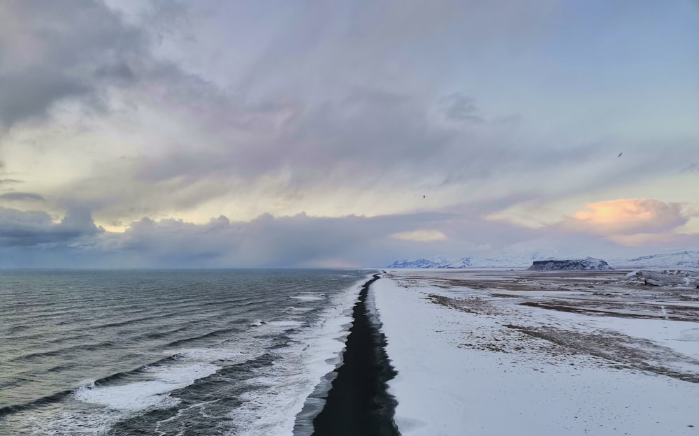 Ein langer schneebedeckter Strand neben dem Meer