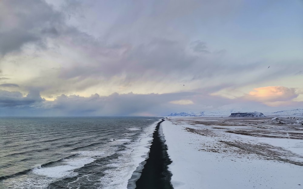 a long stretch of snow covered beach next to the ocean