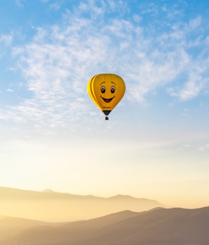 Playful 3D cartoon image of Globee and yellow bunny waving from their colorful hot air balloon floating among soft clouds