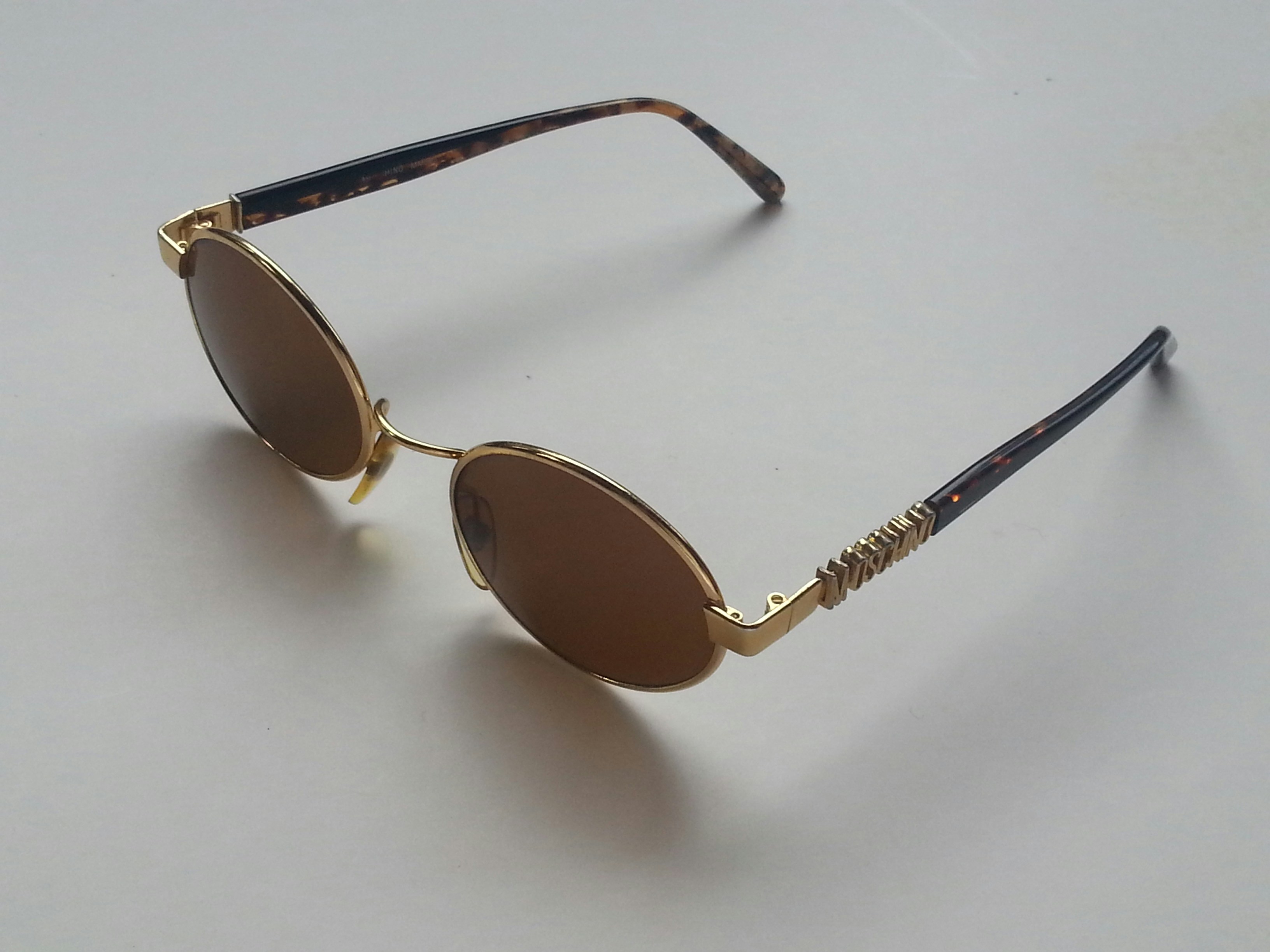 Brown tortoise-shell sunglasses with gold hardware on white background