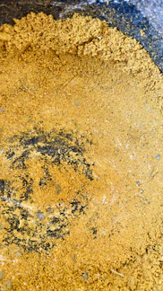 Close-up of dark, fine humic acid powder spilling from a burlap sack.