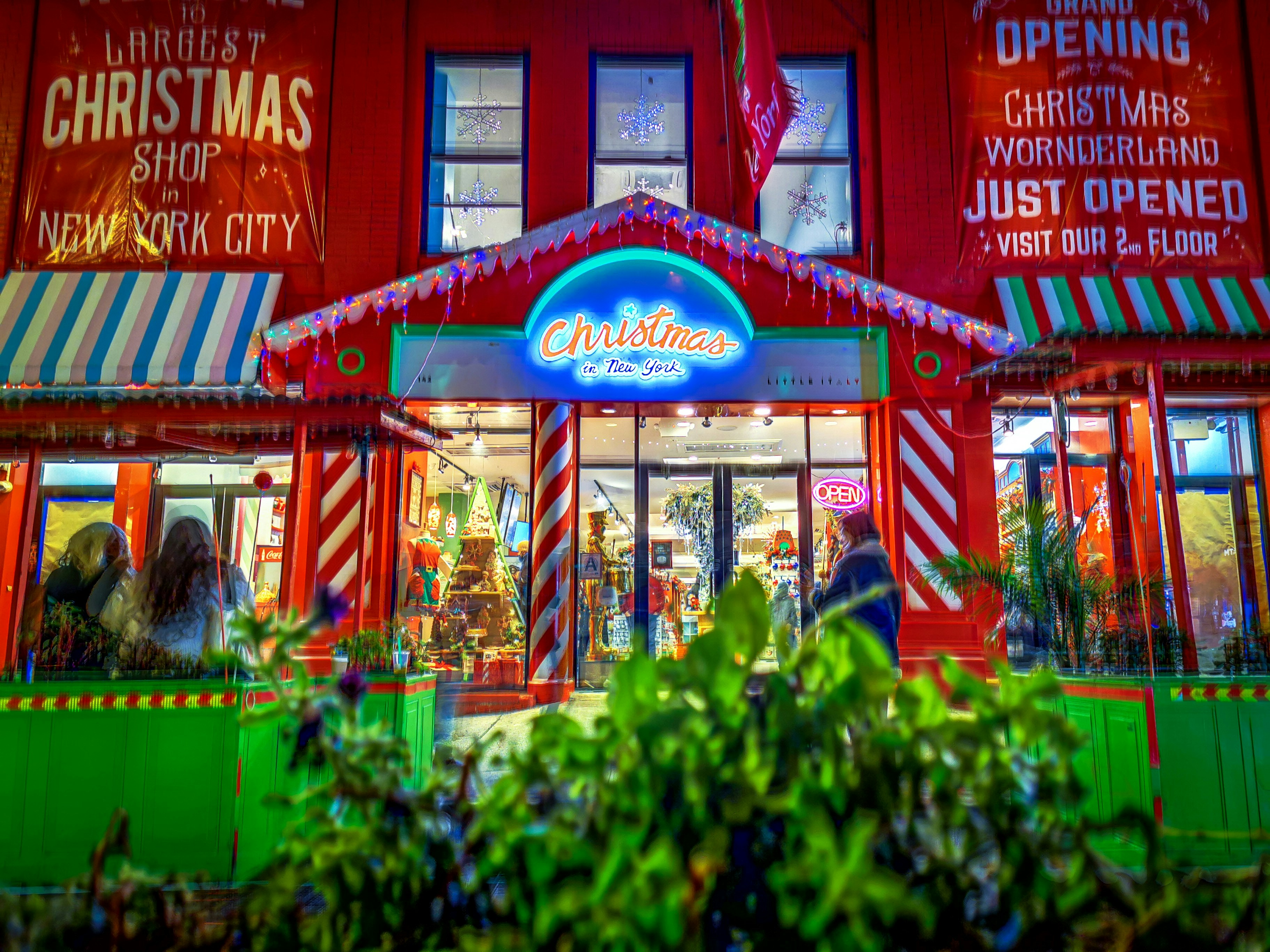 a brightly lit christmas store front at night, 