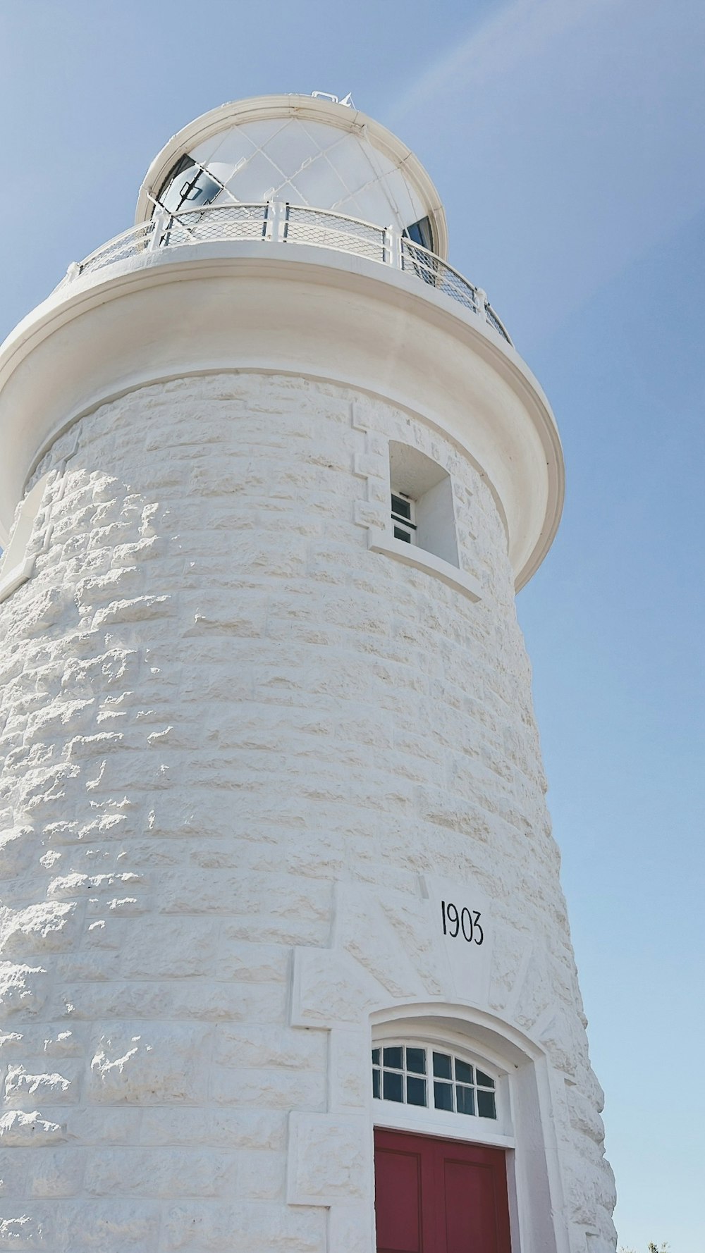 a white lighthouse with a red door on a sunny day