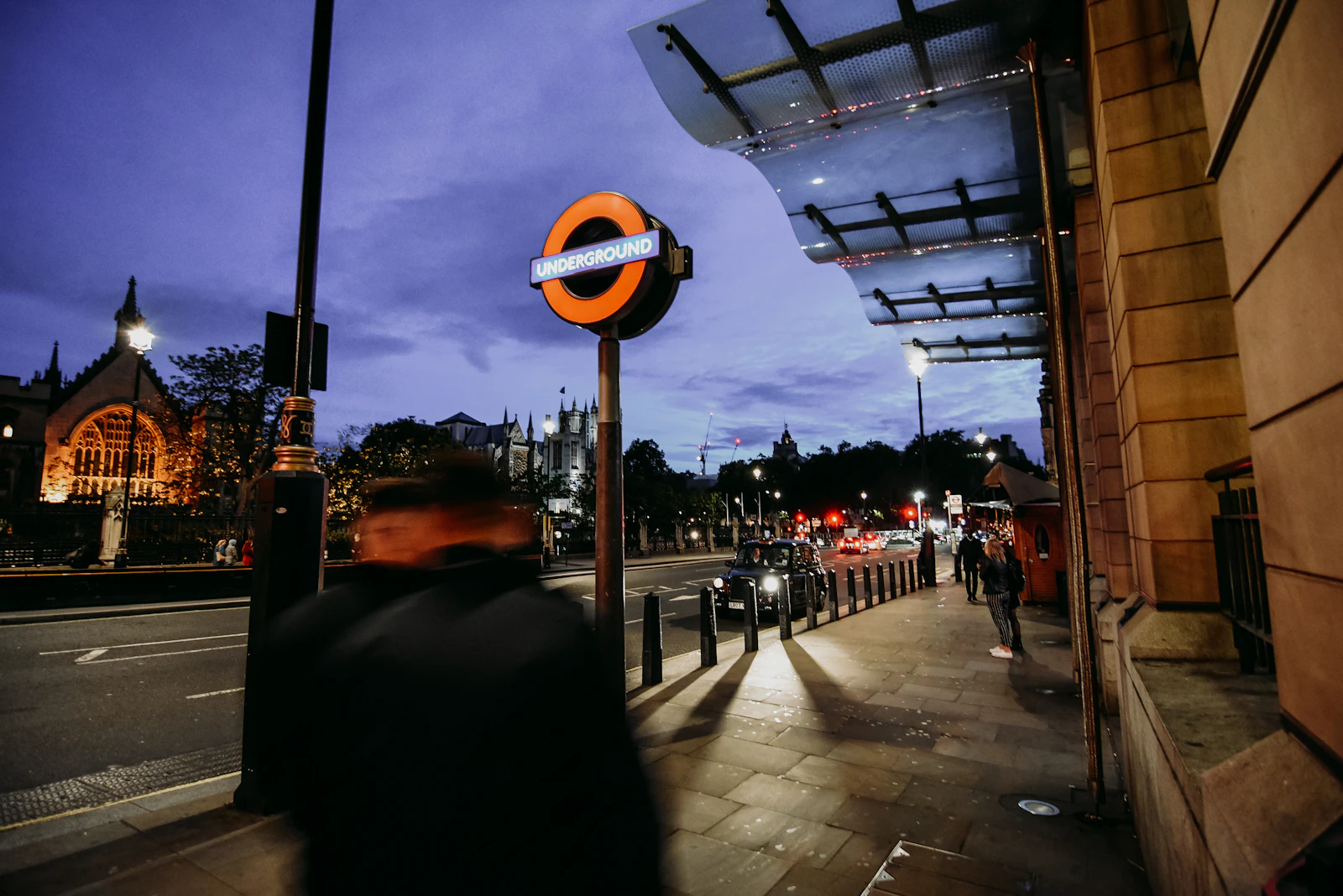 A figure standing still on a London street as the city moves around them