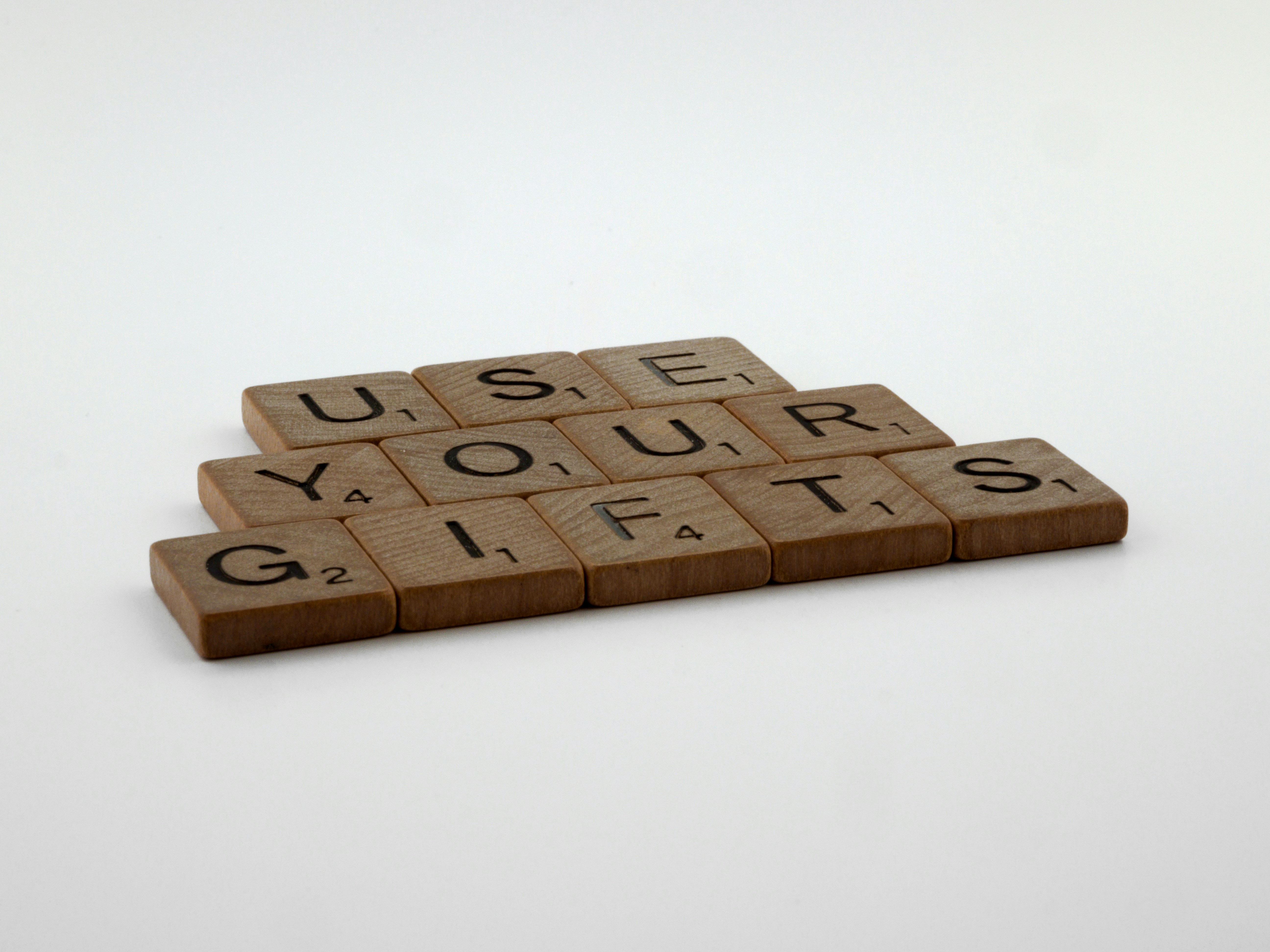 scrabble, scrabble pieces, lettering, letters, wood, scrabble tiles, white background, words, quote, letters, type, typography, design, layout, focus, bokeh, blur, photography, images, image, use your gifts, gifting, christian, st paul, paul, spiritual gift, charism, charismata, holy spirit, word of knowledge, faith, healing, miracle, prophecy, discernment, tongues, apostle, prophet, corinthians, romans, ephesians, 1 peter, serving, teaching, exhortation, encouragement, giving, leadership, mercy, love,