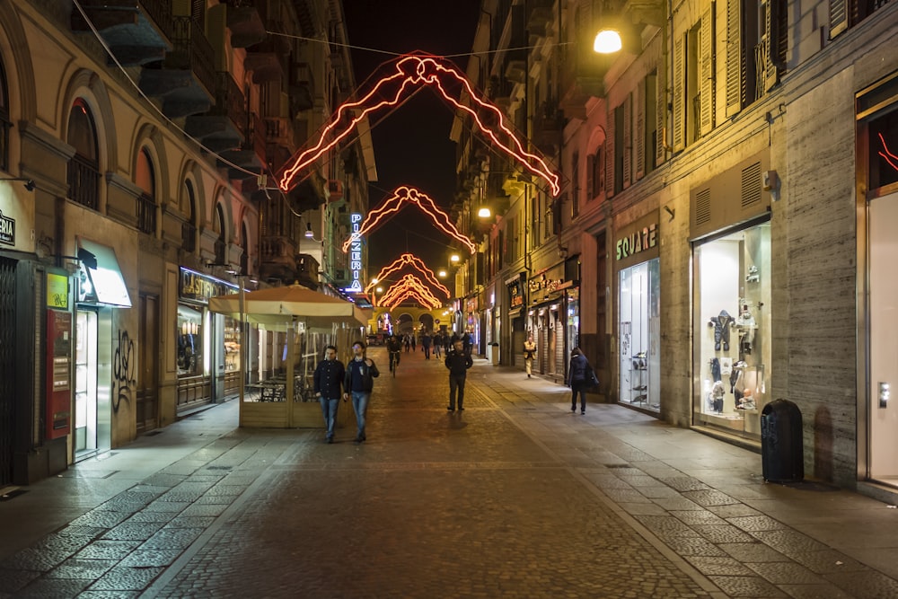 a city street at night with people walking down it