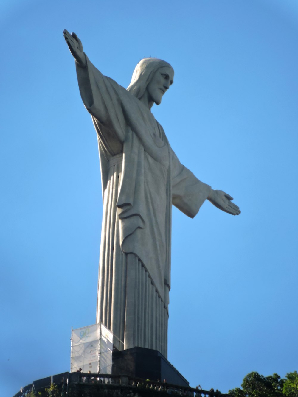 the statue of jesus is in the middle of a clear blue sky