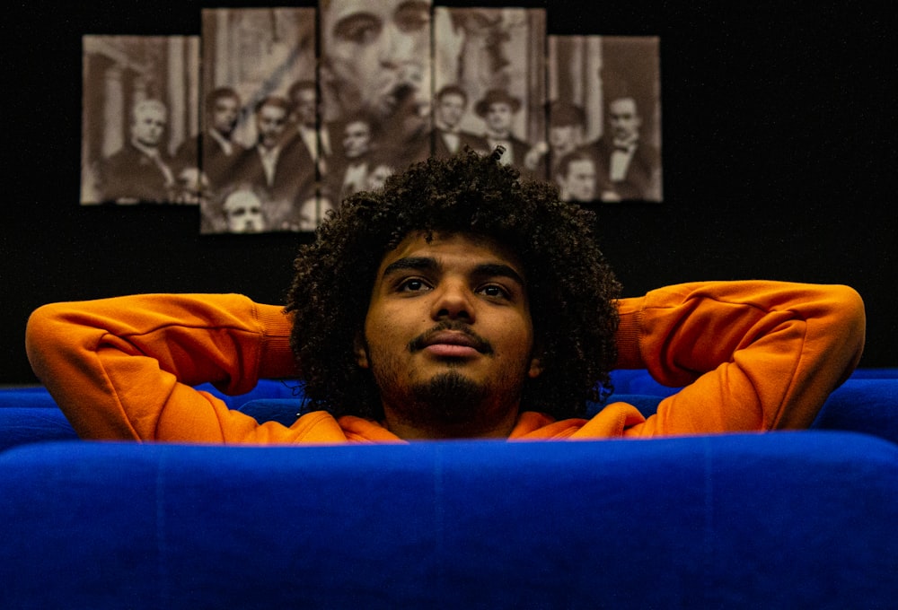 a man sitting on a blue couch with his hands on his head