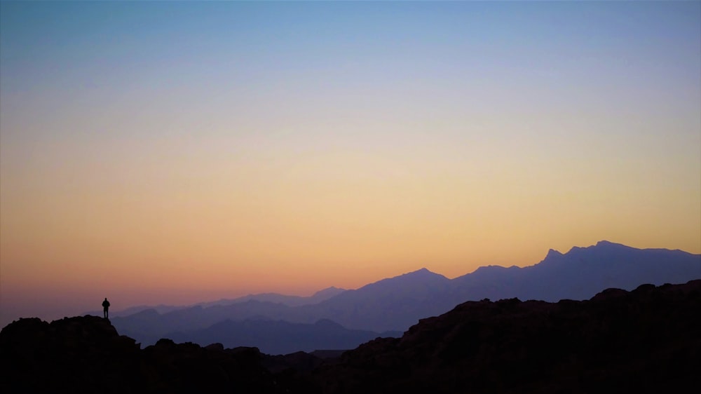 a person standing on top of a mountain at sunset