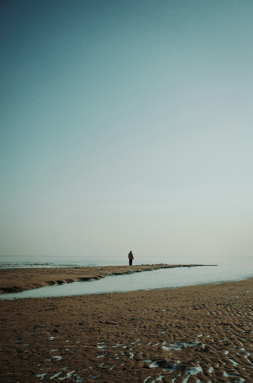 a person standing on a beach next to a body of water