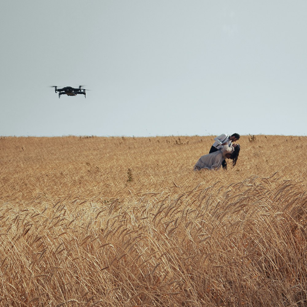 two people in a field with a helicopter in the background