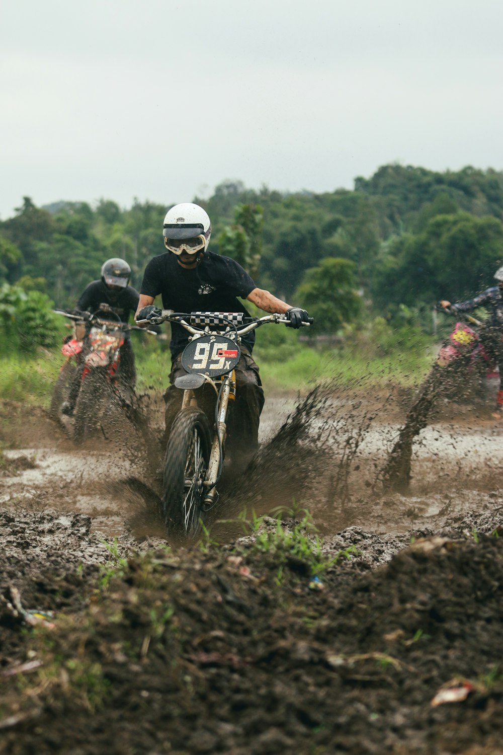 a group of people riding dirt bikes on a muddy road