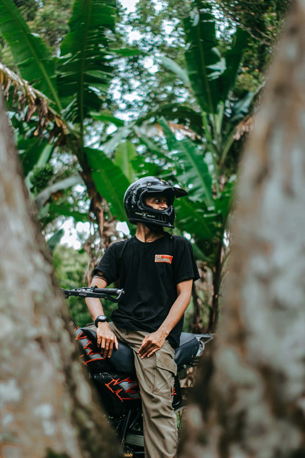 a man sitting on a motorcycle in a forest