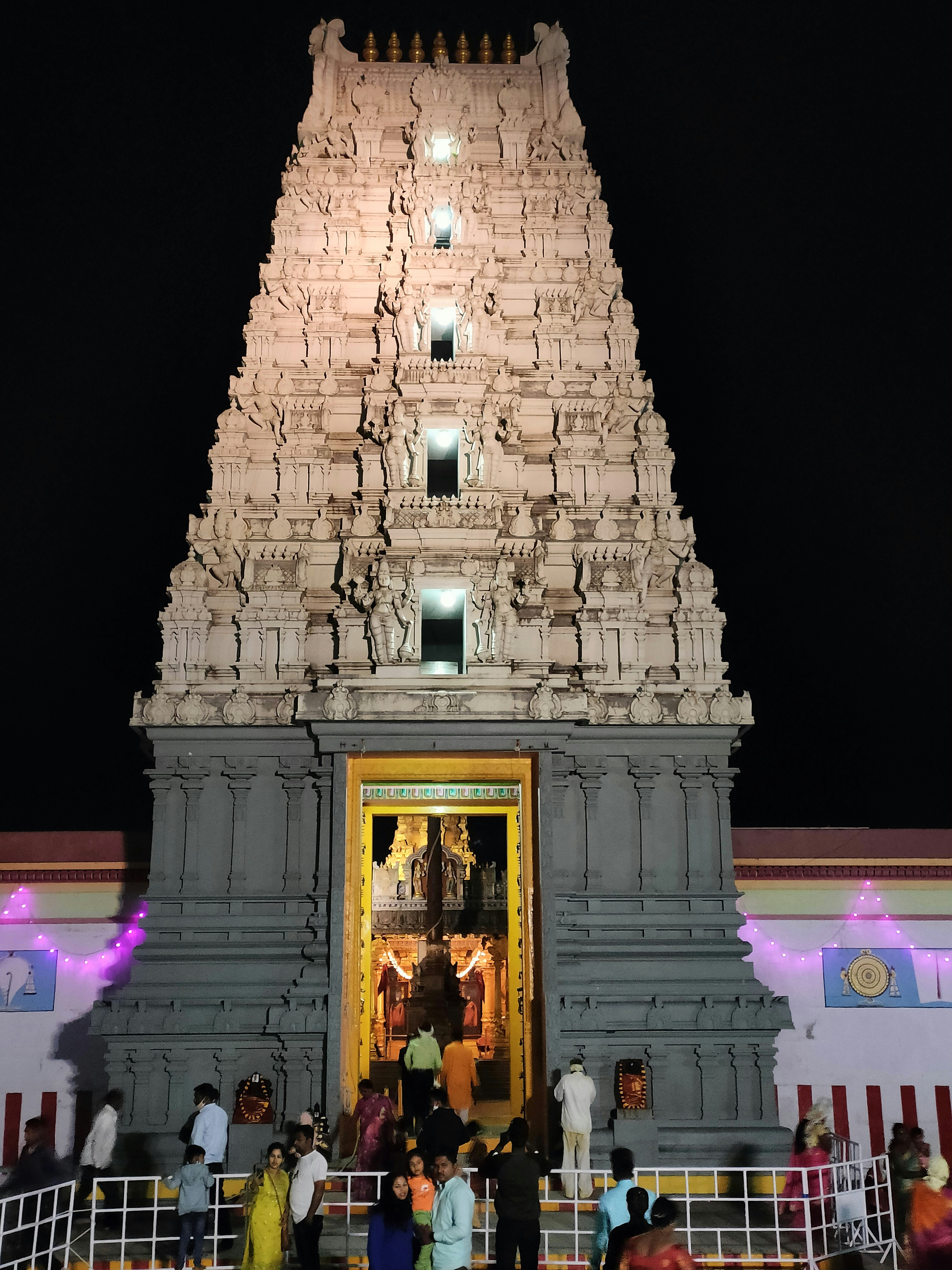 Ambaji temple illuminated at night with devotees performing evening aarti