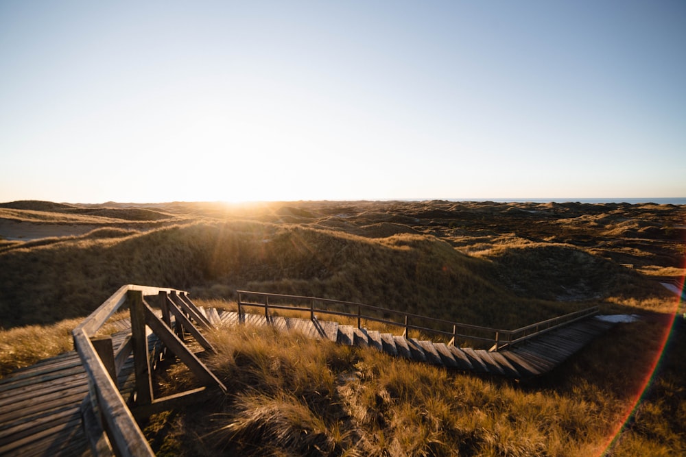 a wooden bench sitting on top of a grass covered hillside