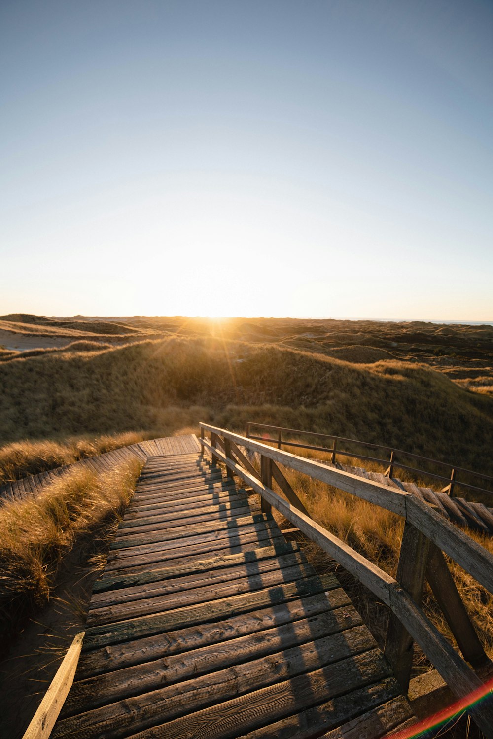 a wooden walkway leading to a grassy field