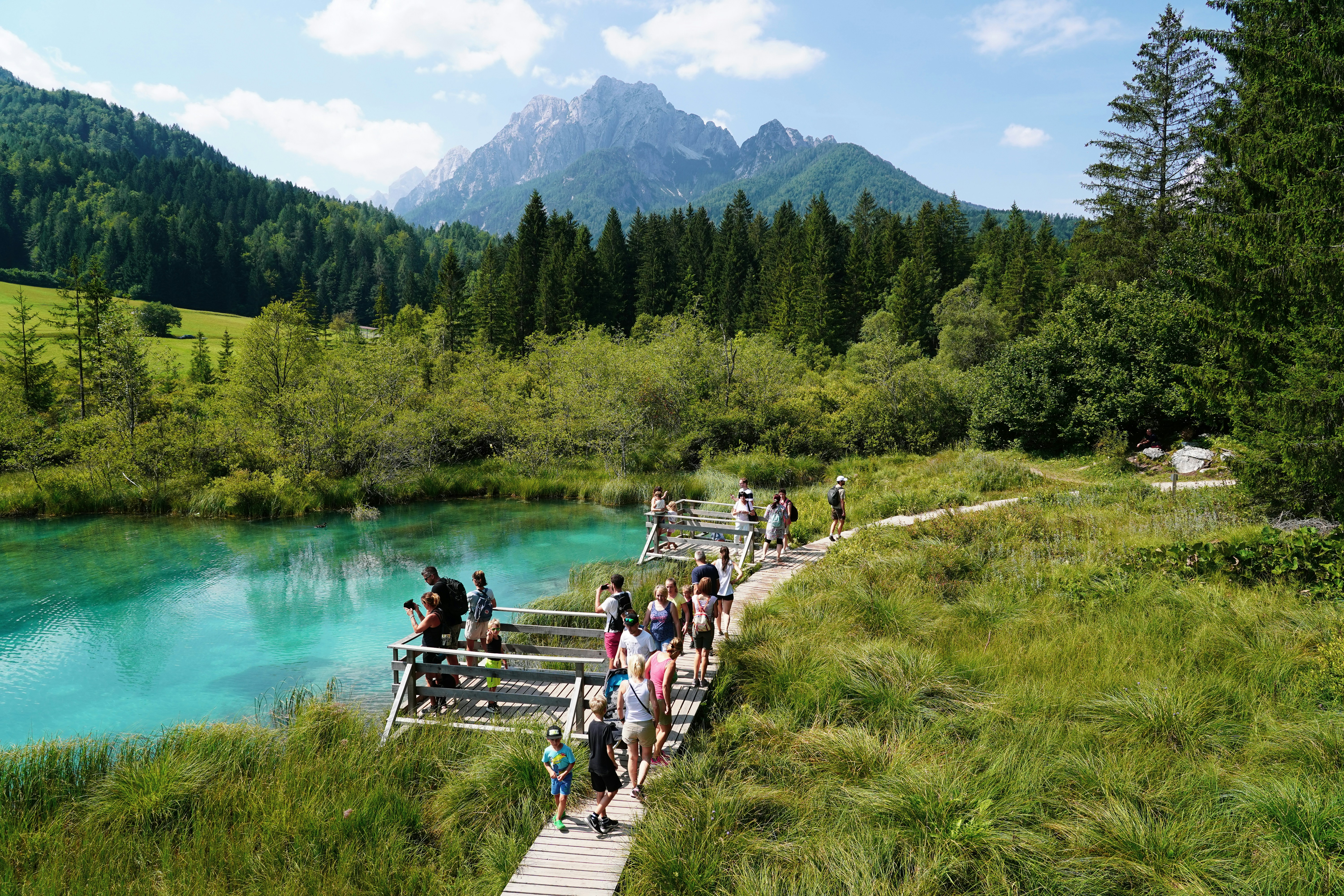 a group of people walking across a bridge over a river