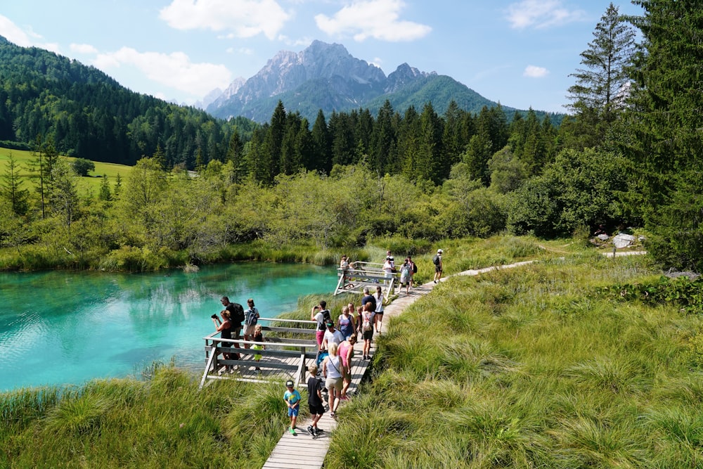 a group of people walking across a bridge over a river