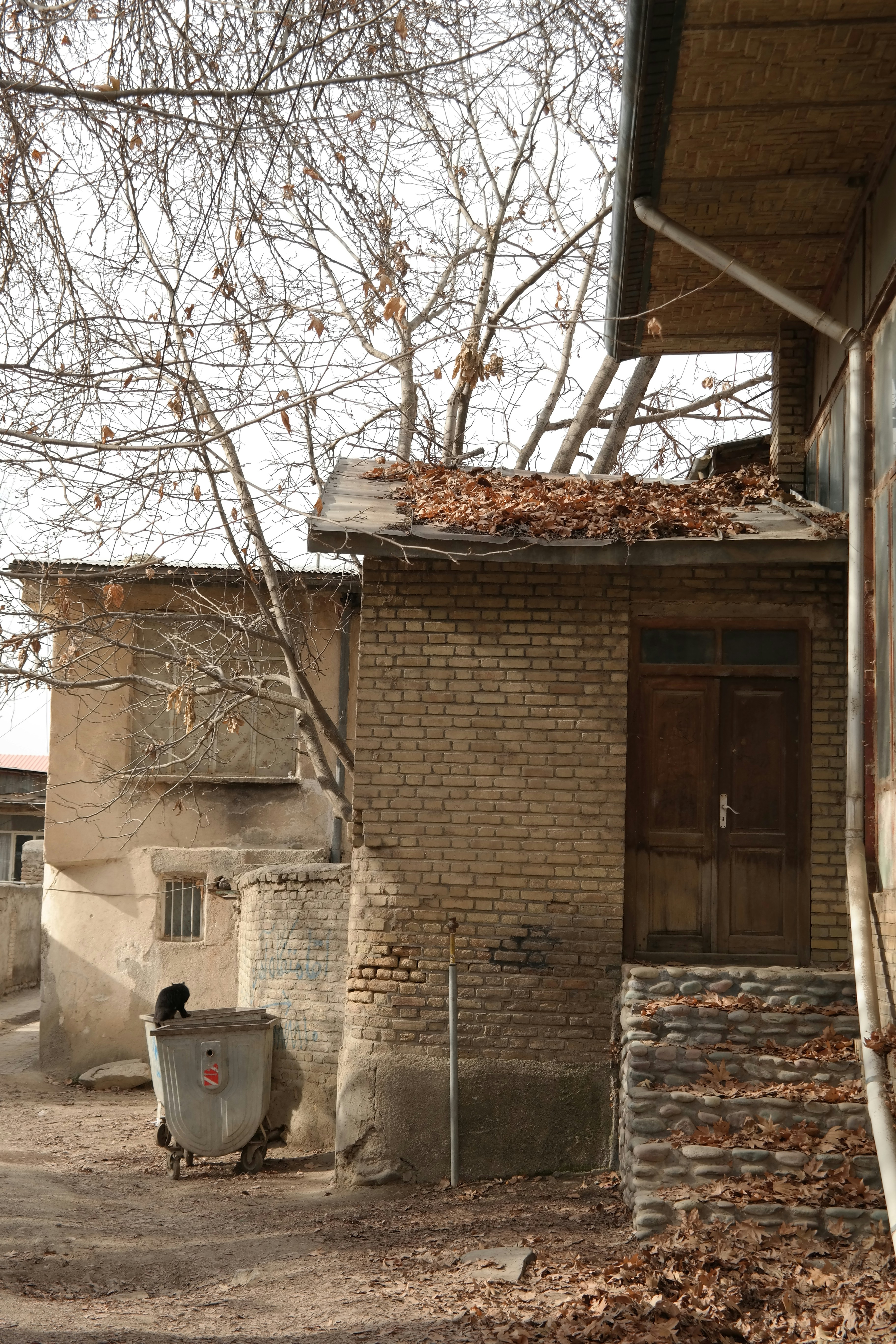 An old brick building with a trash can in front of it