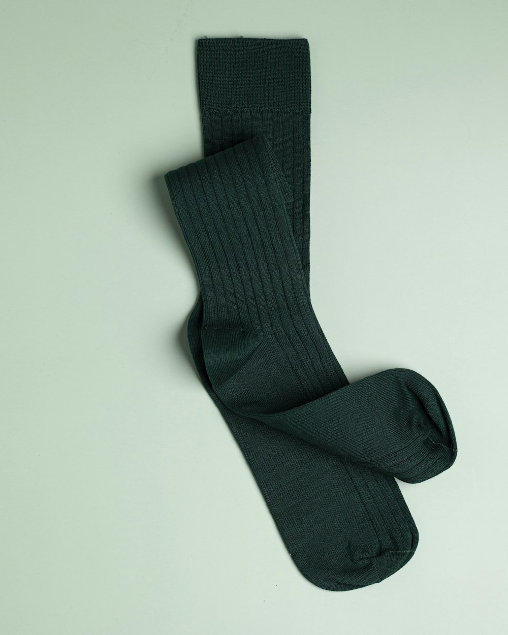 a pair of green socks laying on top of a white surface