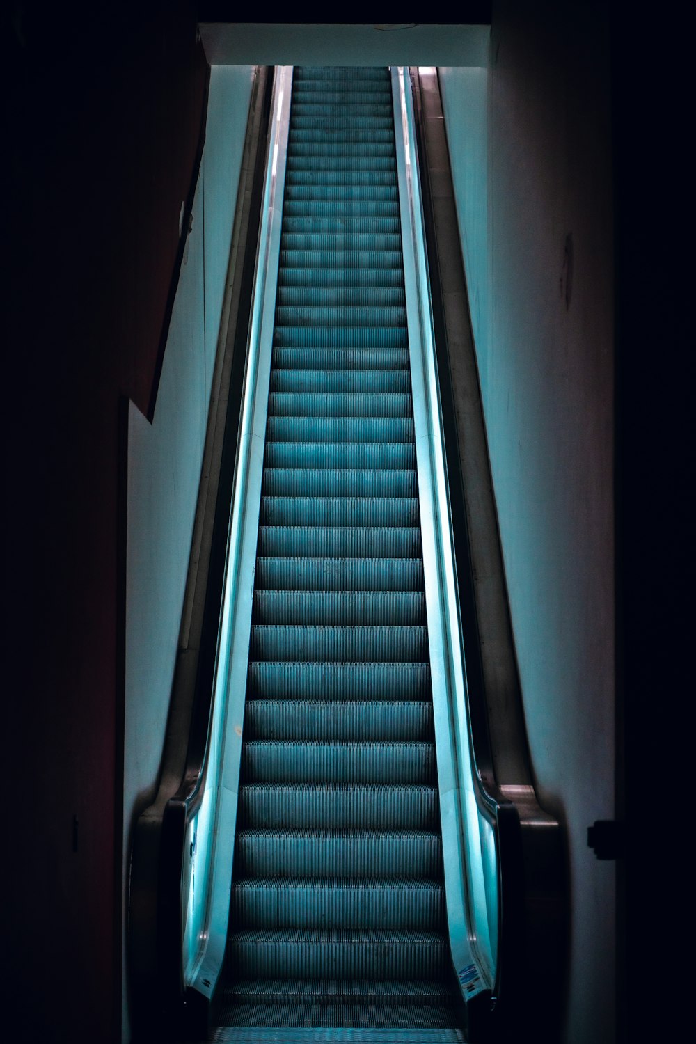 an escalator in a building with blue lights