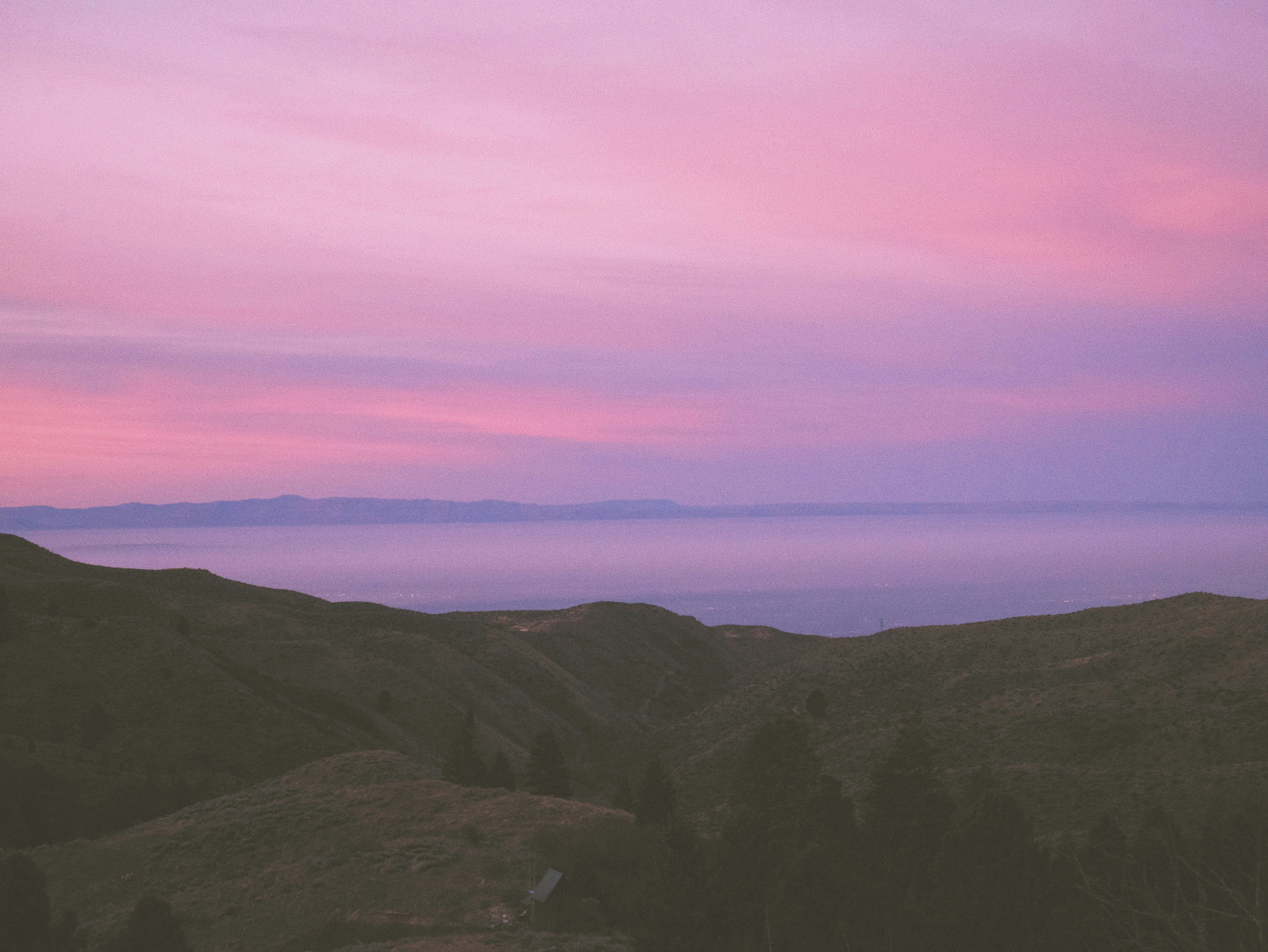 a pink and purple sky over a mountain range