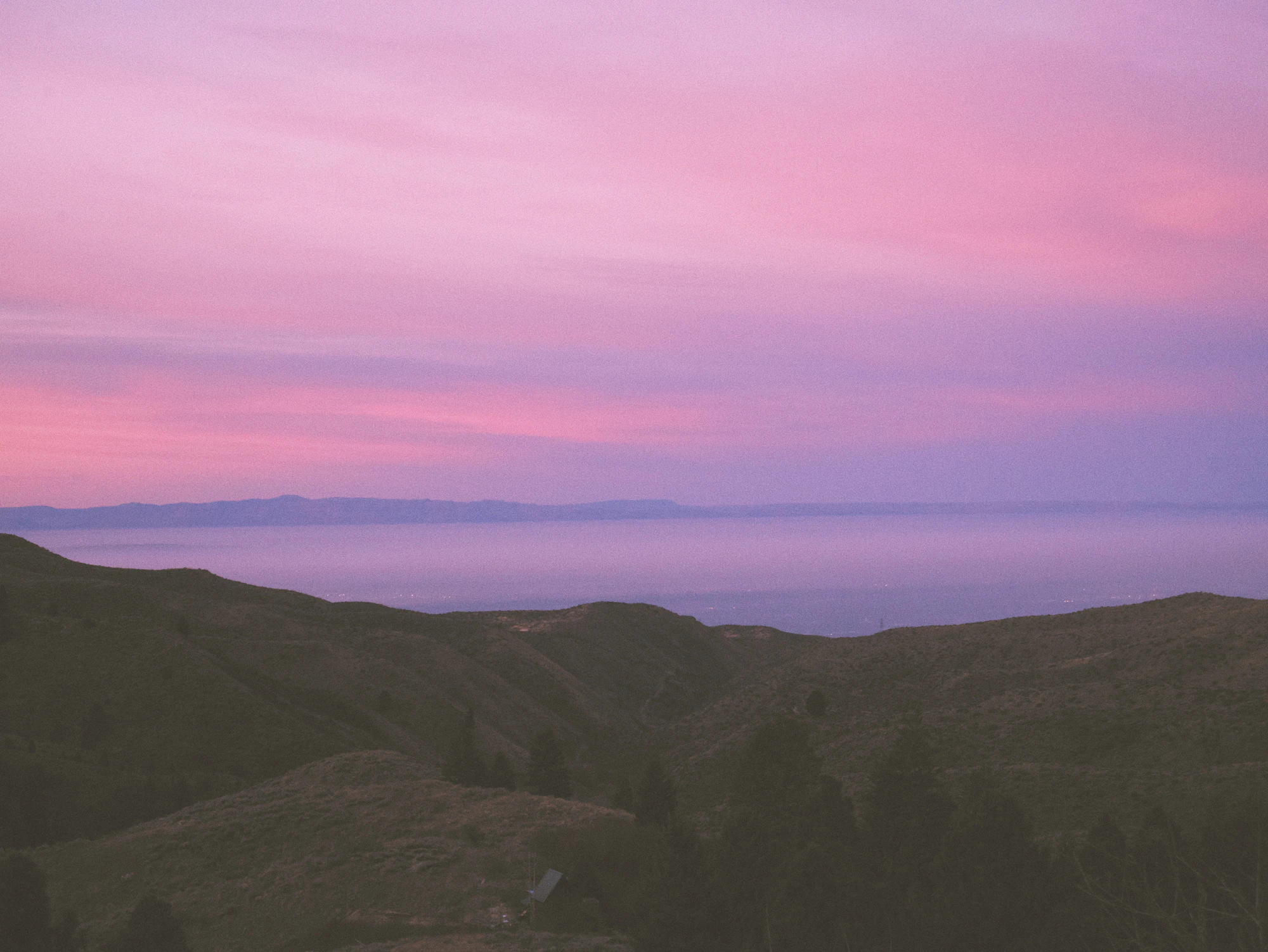 Mountain range beneath a soft pink and gold sky