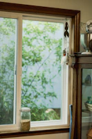 A cozy kitchen scene featuring a bright ceramic pitcher filled with fresh flowers beside a window.
