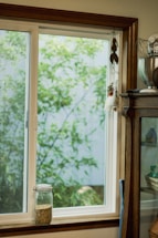 A bright farmhouse kitchen scene with mason jars filled with dried herbs and a curious chicken peeking in.